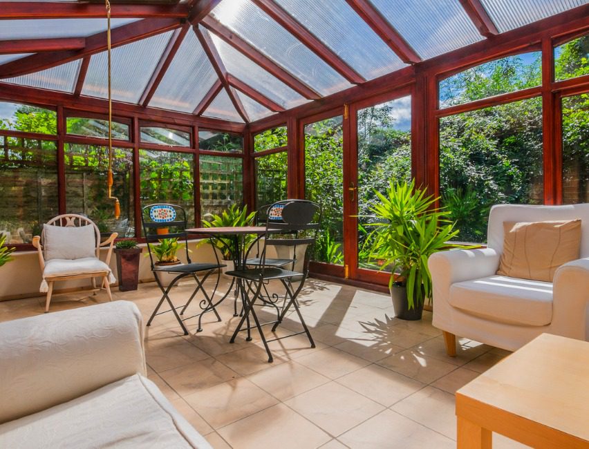 Sunroom with red beams and cream colored furniture